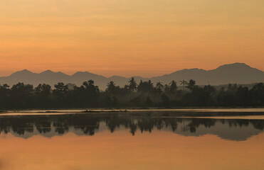 Naklejka premium Beautiful natural scenery of lake in southeast Asia .Mountain reflextion and shilouettes in the calm water