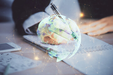 Social network theme hologram over hands taking notes background. Concept of global international people connect. Double exposure