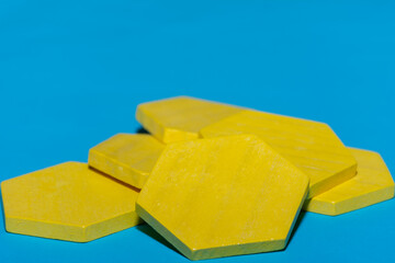 Bright colored yellow tangram child geometric shape puzzle pieces  in a pile close up on blue background with copy space.