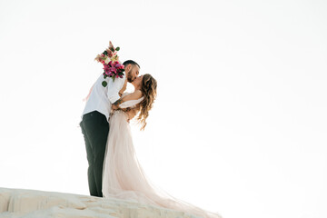 Love Story of a beautiful couple in a pink wedding luxury dress with a bouquet in the Sahara...