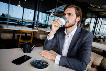 Handsome man in a business suit drinks coffee in a restaurant