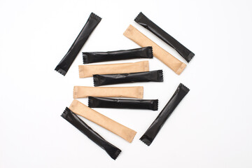Sugar sticks on a white background. Sugar sticks without logo. Craft paper sugar bags. Sugar bags made of black paper. Mockup for applying a logo.