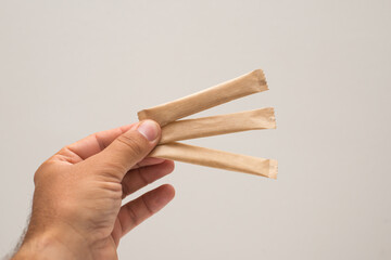 A man's hand holds a sugar stick. Sugar bag without logo. Sugar stick for logo.