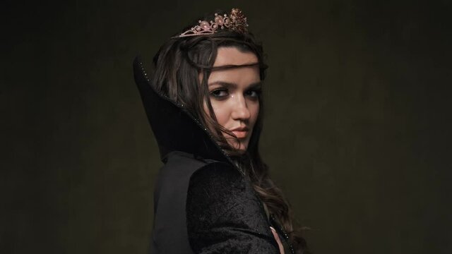 Beautiful queen at dark background. Portrait of vampiress looking at camera. Halloween concept. Close-up shot in 4K, UHD