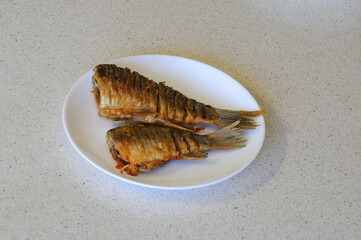 fried river fish crucian carp on a white plate. home kitchen
