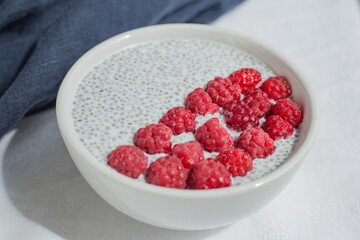 Chia seed pudding with fresh raspberries and coconut milk in white bowl. Concept of healthy eating, healthy lifestyle, dieting, fitness menu.