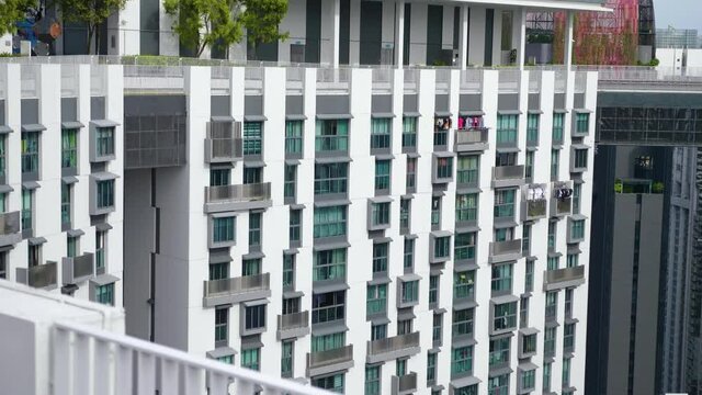 Amazing rooftop garden. Beautiful outside terrace with park and scenic city view. Modern benches under green trees along walkway. Urban eco design and mini-ecosystem. Landscaping in Singapore.