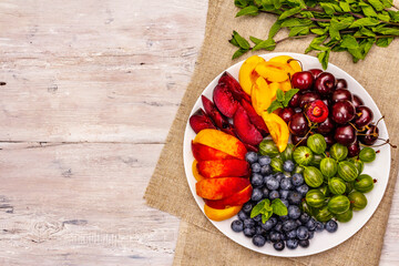Assorted fresh berries of a cherry, gooseberry, blueberries, slices of ripe peach, plum and...