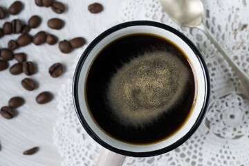 Coffee in a mug and some coffee beans in the background.