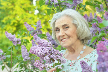 Close-up portrait of happy senior beautiful woman with lilacs