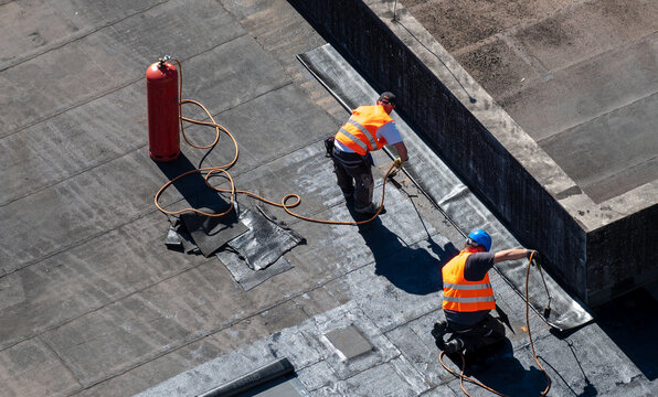 Birds eye view of a roof construction site. Professional bitumen waterproofing on a flat building.