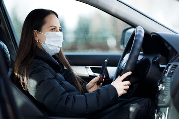 a young girl in a mask sits in a car wearing a protective mask. pandemic