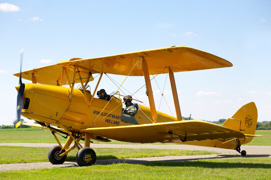 HILVERSUM, NETHERLANDS - JULI 13, 2020: Yellow Tiger Moth De Havilland DH-82A. A biplane from the 1930's used to train World War II pilots. Just landed after a successful flight