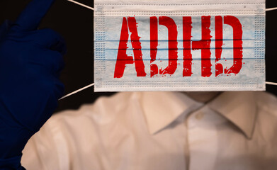 Young boy holds ADHD text written on sheet of paper. ADHD is Attention deficit hyperactivity disorder. Close up.
