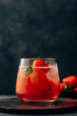 Delicious strawberry cocktail with ice on dark background