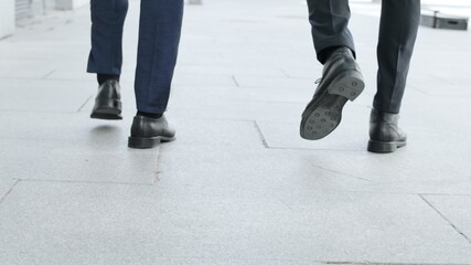Fototapeta premium Businessmen legs walking on urban street together. Colleagues going for work