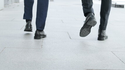 Businessmen legs walking on urban street together. Colleagues going for work