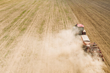Fototapeta premium Aerial View. Tractor With Seed Drill Machine Sowing The Seeds For Crops In Spring Season. Beginning Of Agricultural Spring Season. Countryside Rural Field Landscape