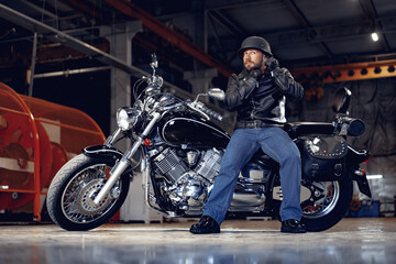 Plakat Biker man in leather jacket and helmet sitting on his motorcycle