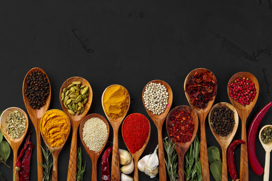 Various Exotic Spices In Wooden Spoons On Dark Background