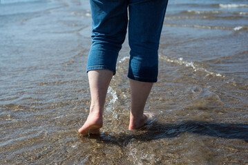 Closeup of feet of woman walking in the water in the sea