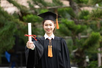 Attractive Asian Women Student Graduate in cap and gown celebrating