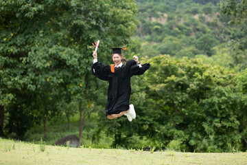 Asian Women Graduate in cap and gown celebrating jump