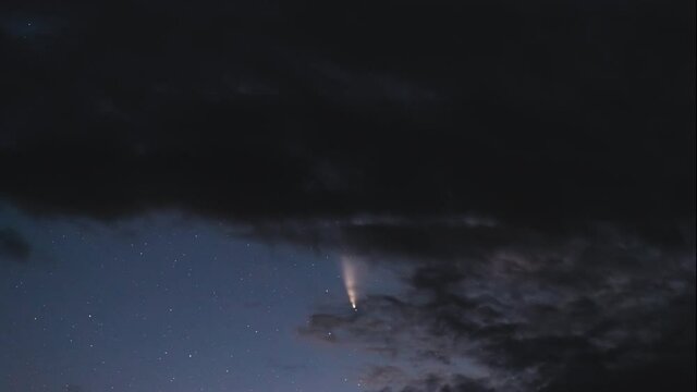 Timelapse of the movement of a large  C/2020 F3 (NEOWISE) comet among clouds in the night starry sky