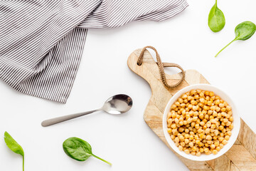 Raw chickpeas in bowl on white kitchen table top view