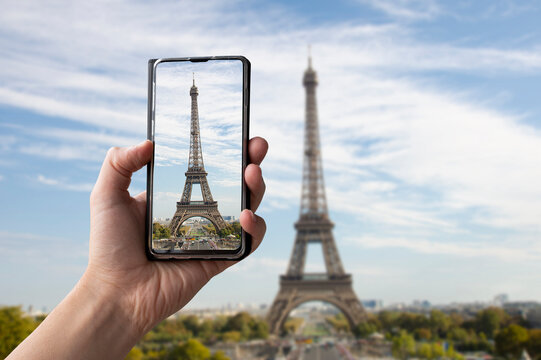 Tourist taking photo of Eiffel tower in Paris, France. Man holding phone and taking picture.