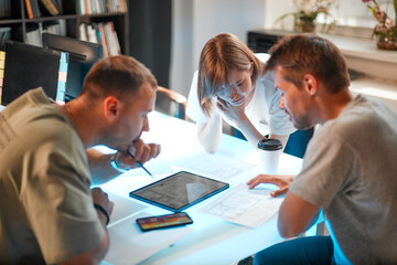 Young creative team of designers developing a new interior project using tablet and phone with palette in modern studio