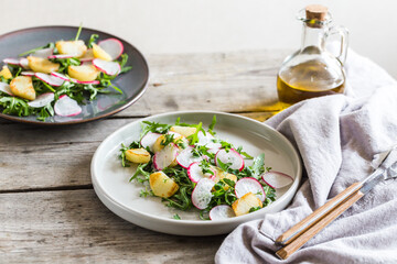 fresh salad with arugula, radish, baked potatoes and aromatic herbs with olive oil