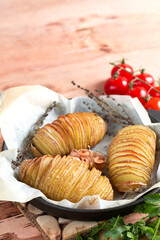 Hasselback potatoes. Baked potatoes in pan on wooden table