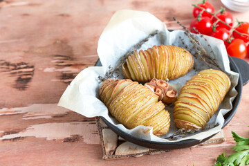 Hasselback potatoes. Baked potatoes in pan on wooden table