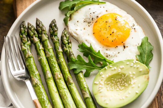 Healthy homemade breakfast with asparagus, fried egg, avocado and arugula. quarantine healthy eating concept. keto diet