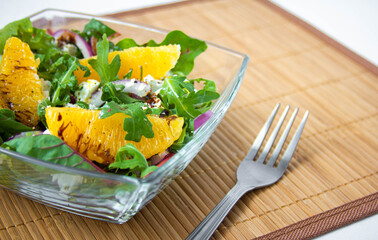 Salad with oranges, feta and arugula on wood background
