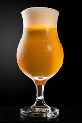glass of beer with froth and cold sweat, dark background in vertical orientation