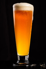 glass of beer with froth and cold sweat, dark background in vertical orientation