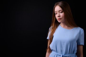 Young beautiful woman with long brown hair against black background