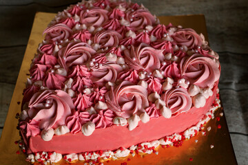 pink heart-shaped cake decorated with cream in the form of curls and roses, sweetness for Valentine's day
