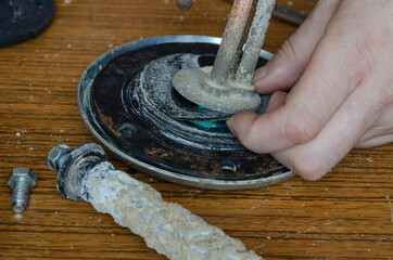 Close-up of a man's hands showing a torn rubber gasket for a water heater.