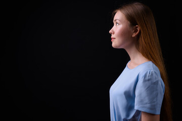 Young beautiful woman with long brown hair against black background