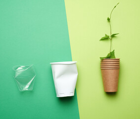 plastic drink cups and paper cup with branch and green leaves on green background, environmental pollution concept, no plastic