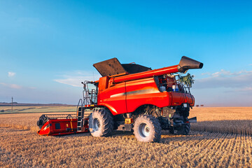 Harvesting grain in the field, harvester close-up. Bright, summer, daytime landscape.