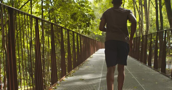 Back view on african american guy jogging in park