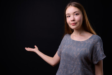 Young beautiful woman with long brown hair against black background