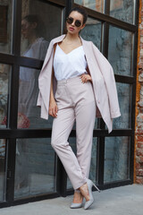 Naklejka premium model posing with glasses. girl in pants and with a jacket. life style