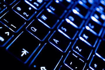 Close up view of a modern laptop computer keyboard key with blue buttonss. Pc computer keyboard close up