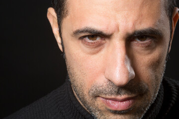 Ritratto stretto di un uomo che guarda con espressione dura e severa isolato nell'oscurità