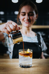 Barista girl prepares a refreshing summer version of iced and syrup coffee - an unconventional recipe
